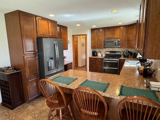 kitchen featuring a kitchen breakfast bar, kitchen peninsula, tasteful backsplash, and appliances with stainless steel finishes