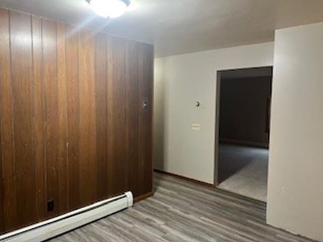 empty room featuring hardwood / wood-style floors and a baseboard radiator