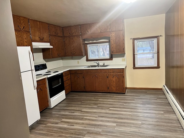 kitchen with light wood-type flooring, white appliances, baseboard heating, and sink