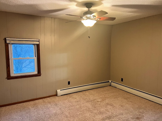 carpeted empty room with ceiling fan, baseboard heating, a textured ceiling, and wooden walls