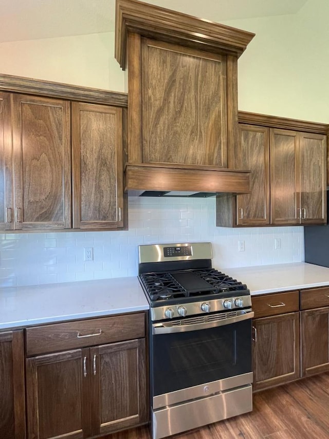 kitchen featuring backsplash, vaulted ceiling, dark wood-type flooring, and stainless steel gas range