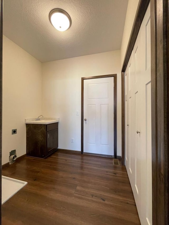 washroom with cabinets, a textured ceiling, dark hardwood / wood-style floors, and electric dryer hookup