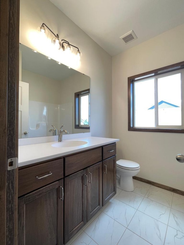 bathroom featuring toilet, vanity, a healthy amount of sunlight, and walk in shower