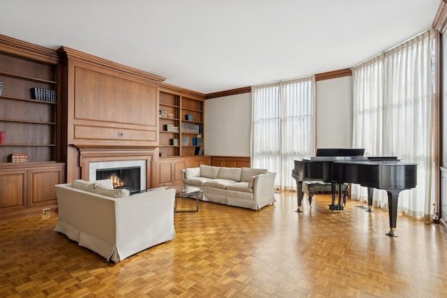 living room featuring ornamental molding, a fireplace, built in features, and light parquet flooring