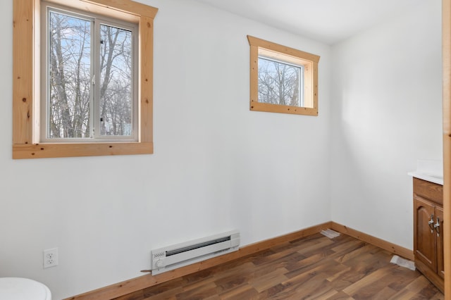 interior space featuring a baseboard heating unit, dark hardwood / wood-style floors, and a healthy amount of sunlight