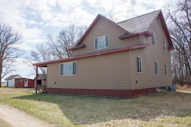 61684 260th St, Hewitt, MN 56453 - view of side of property featuring a shingled roof, a yard, and central AC unit