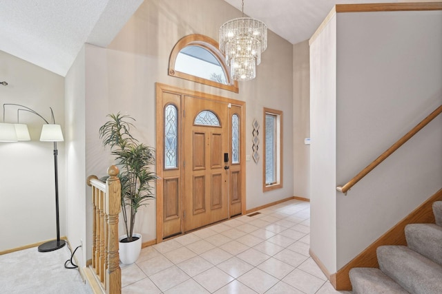 foyer entrance featuring high vaulted ceiling, light tile patterned floors, a chandelier, and a textured ceiling