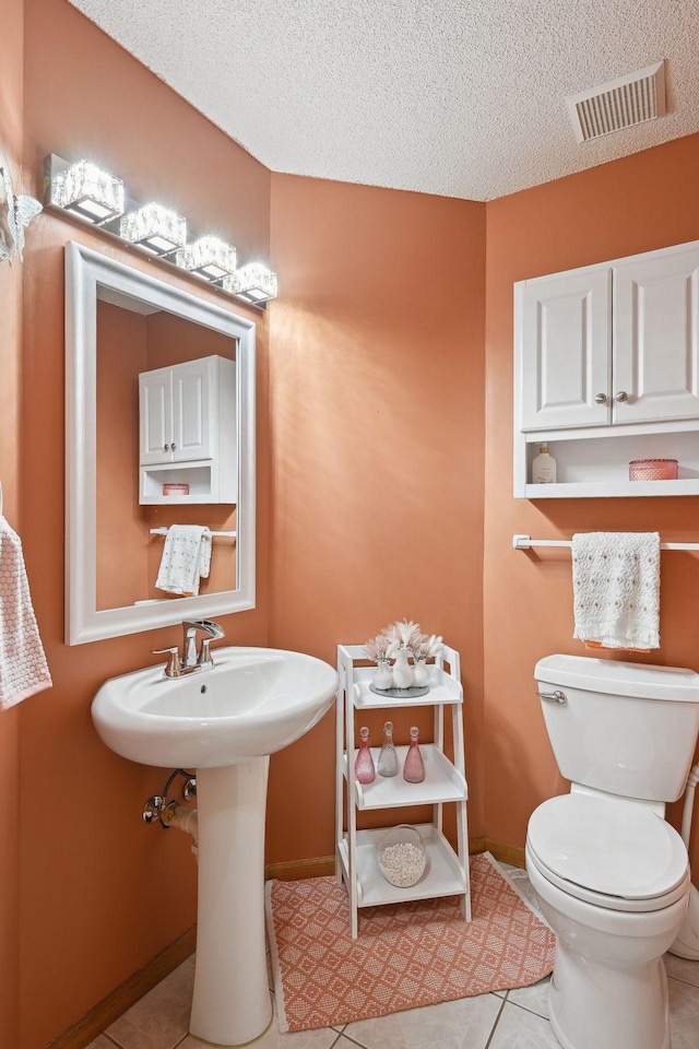 bathroom with a textured ceiling, tile patterned floors, and toilet