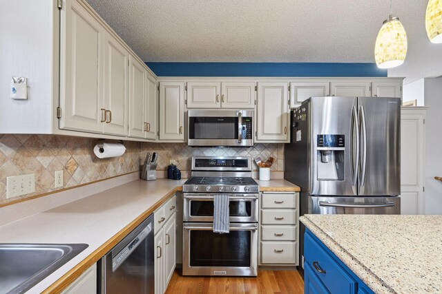 kitchen featuring hanging light fixtures, appliances with stainless steel finishes, a textured ceiling, and tasteful backsplash