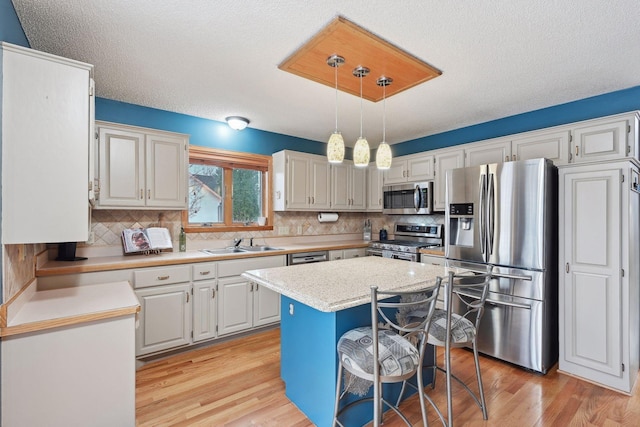 kitchen featuring pendant lighting, a center island, sink, stainless steel appliances, and white cabinets