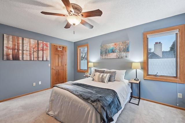 bedroom with ceiling fan, light colored carpet, multiple windows, and a textured ceiling