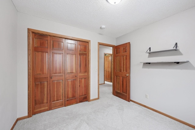 unfurnished bedroom with a textured ceiling, a closet, and light carpet