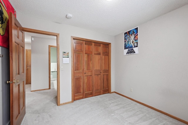 unfurnished bedroom with light carpet, a closet, and a textured ceiling