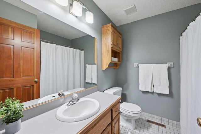 bathroom featuring toilet, vanity, tile patterned flooring, and a textured ceiling