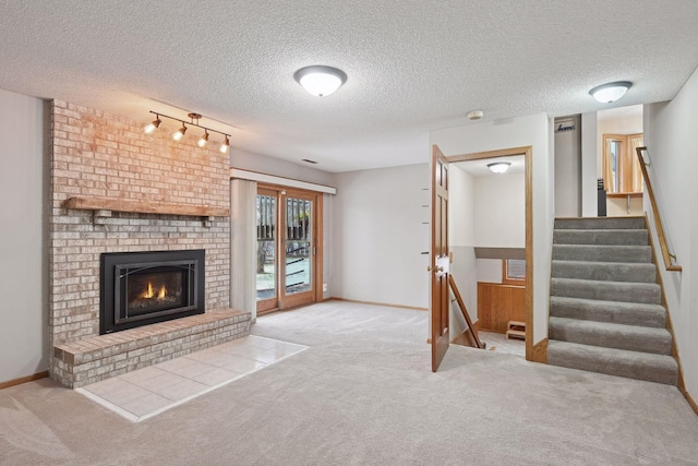 unfurnished living room with a textured ceiling, track lighting, carpet flooring, and a fireplace