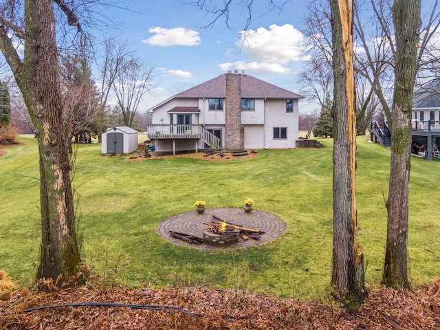 view of yard featuring a deck, a fire pit, and a shed