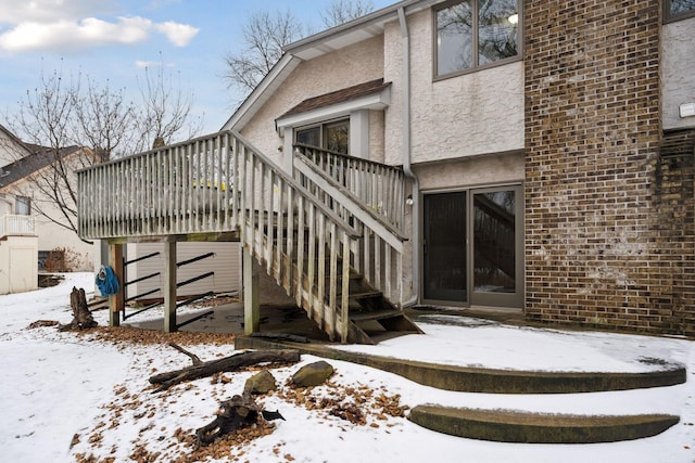 snow covered property entrance featuring a deck