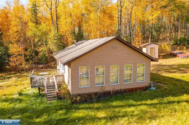 view of side of property featuring a wooden deck, a yard, and a storage shed