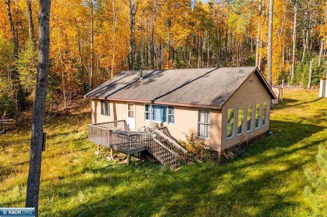 rear view of property featuring a deck and a lawn