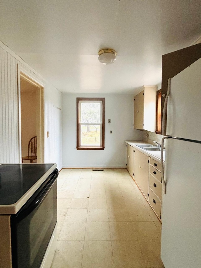 kitchen with electric range, white fridge, and sink