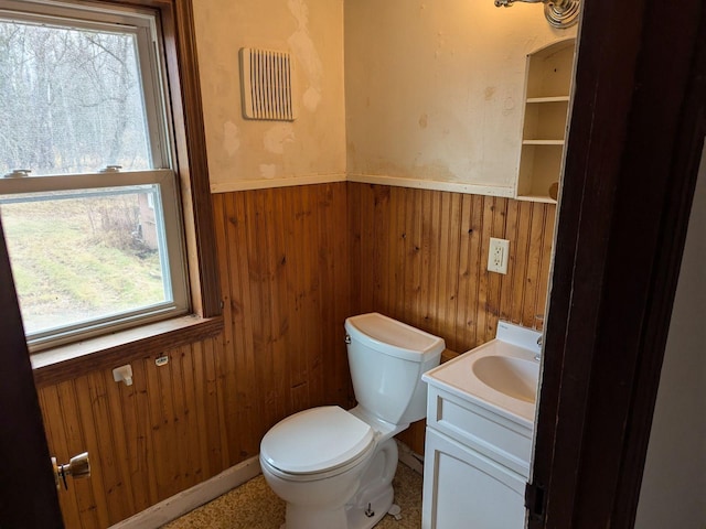 bathroom featuring vanity, toilet, and wooden walls