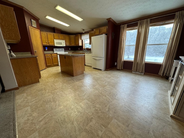 kitchen with sink, a textured ceiling, lofted ceiling, white appliances, and a kitchen island