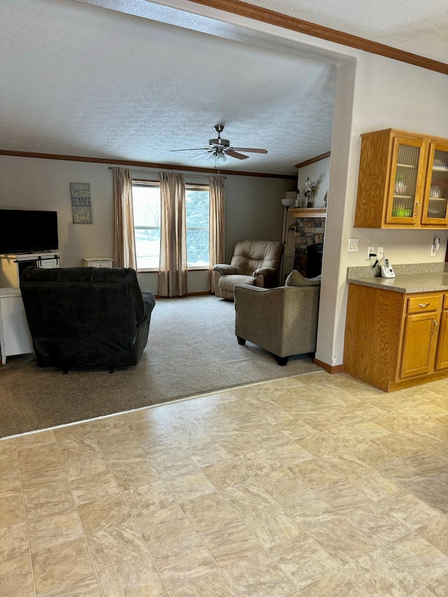 carpeted living room with a fireplace, a textured ceiling, ceiling fan, and crown molding