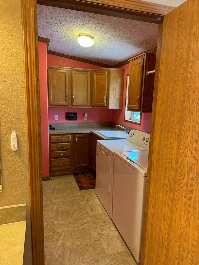 washroom with cabinets, ornamental molding, a textured ceiling, sink, and separate washer and dryer