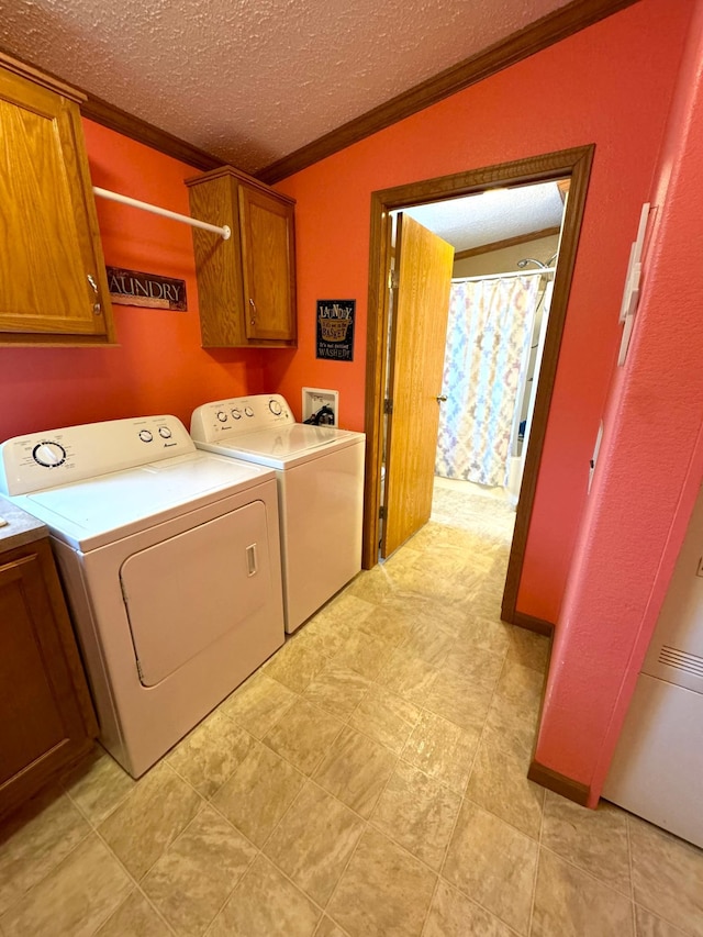 washroom with washer and clothes dryer, cabinets, a textured ceiling, and ornamental molding