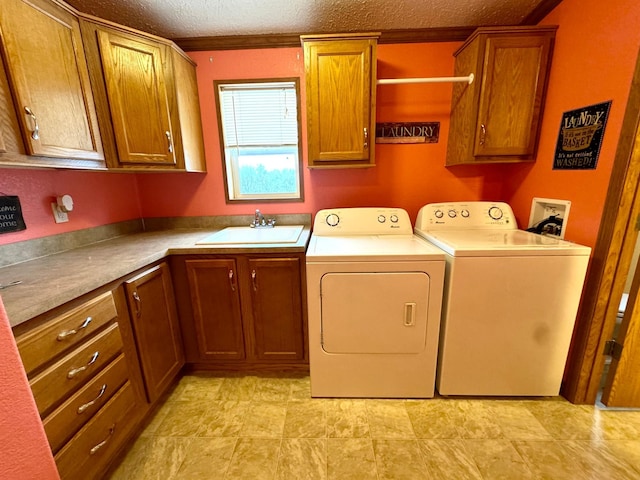 washroom with cabinets, a textured ceiling, crown molding, sink, and separate washer and dryer