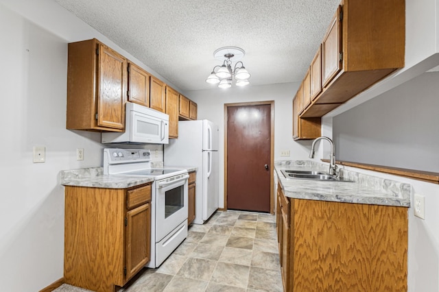 kitchen with a textured ceiling, a notable chandelier, white appliances, and sink