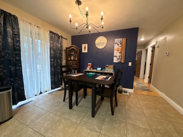 dining area with tile patterned floors, a textured ceiling, and an inviting chandelier