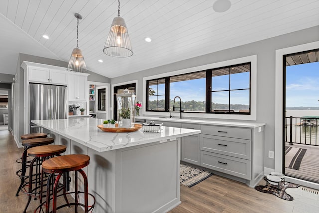 804 County Road I W, Shoreview, MN 55126 - kitchen featuring freestanding refrigerator, a kitchen island, wood finished floors, a breakfast bar, and vaulted ceiling
