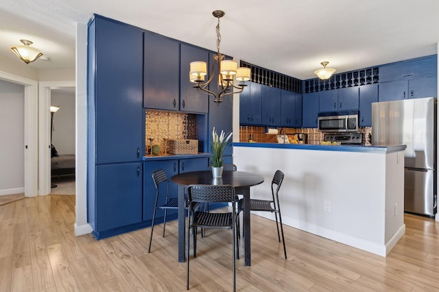 kitchen featuring decorative backsplash, blue cabinetry, appliances with stainless steel finishes, and light wood-style flooring