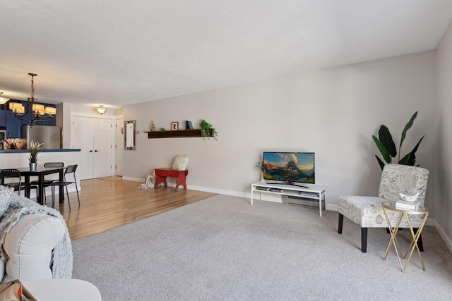 living room featuring baseboards, a notable chandelier, and carpet