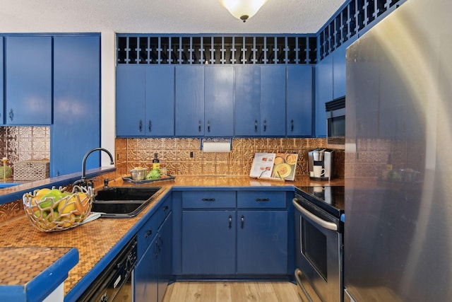 kitchen featuring tasteful backsplash, stainless steel appliances, blue cabinets, and a sink