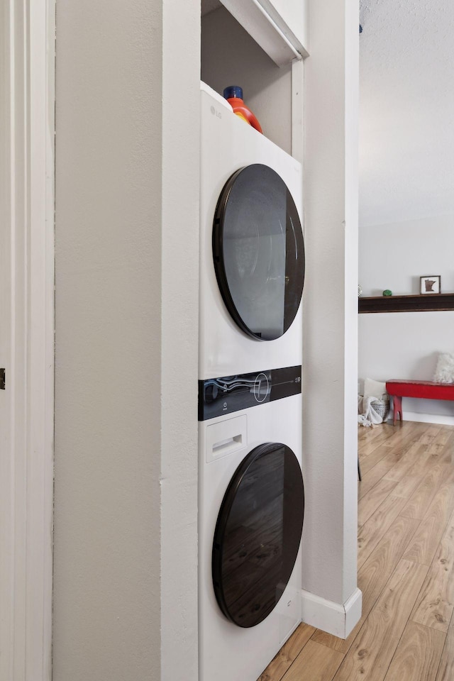 washroom with laundry area, wood finished floors, and stacked washer and dryer