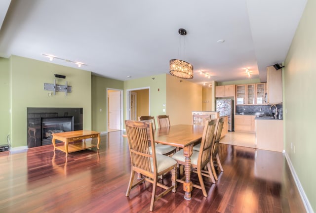 dining area featuring dark hardwood / wood-style flooring, an inviting chandelier, track lighting, and sink