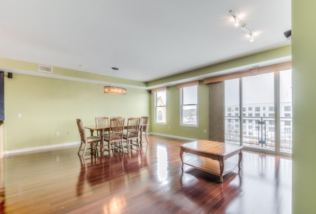 dining area featuring rail lighting, wood-type flooring, and an inviting chandelier