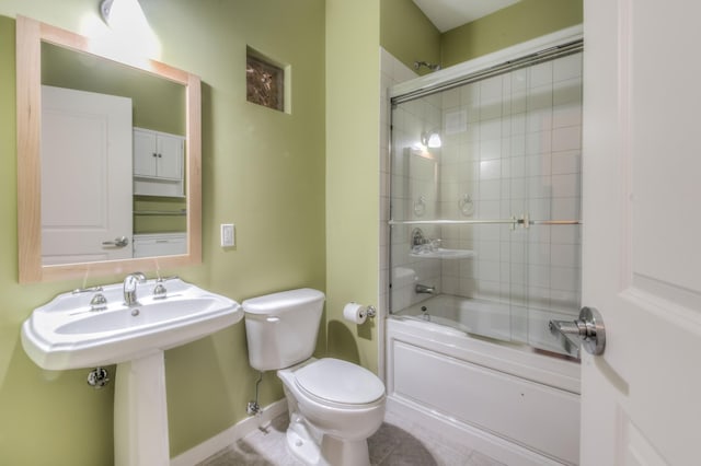 bathroom featuring tile patterned flooring, bath / shower combo with glass door, and toilet