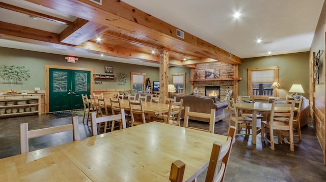 dining area with beamed ceiling, french doors, and a stone fireplace