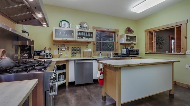 kitchen featuring appliances with stainless steel finishes, dark hardwood / wood-style flooring, butcher block countertops, a kitchen island, and range hood