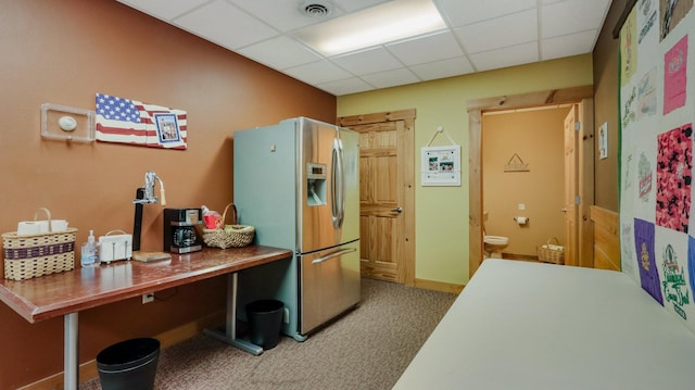 kitchen with a drop ceiling, carpet floors, and stainless steel refrigerator with ice dispenser