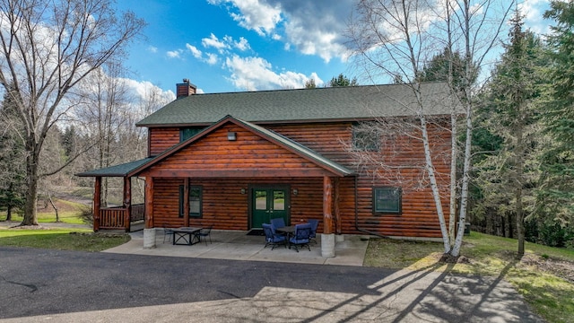 view of front facade featuring roof with shingles, a chimney, and a patio area
