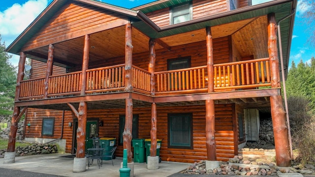 rear view of house featuring a patio area and faux log siding
