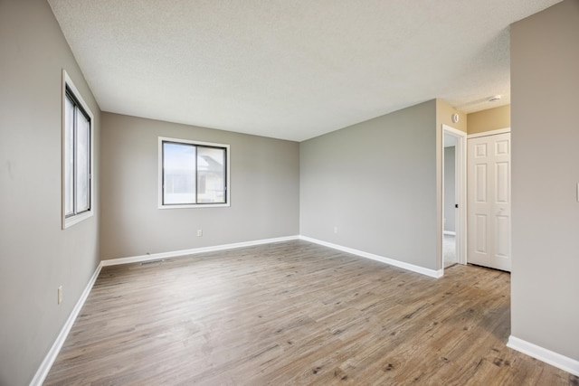 spare room featuring light hardwood / wood-style flooring and a textured ceiling