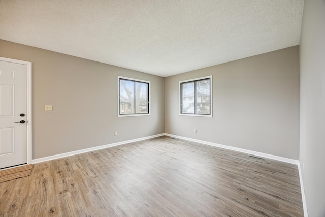 empty room with wood-type flooring and a textured ceiling