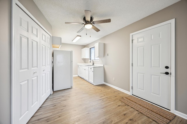 kitchen with ceiling fan, sink, white refrigerator, light hardwood / wood-style flooring, and white cabinetry