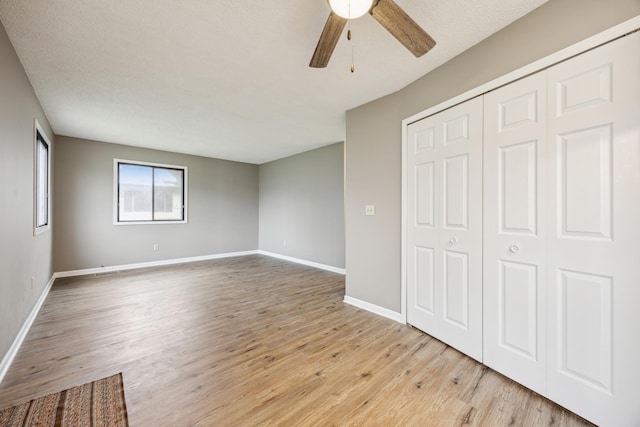 unfurnished bedroom with ceiling fan, a closet, a textured ceiling, and light wood-type flooring