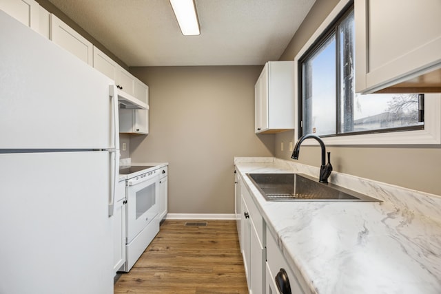 kitchen with white cabinets, wood-type flooring, white appliances, and sink